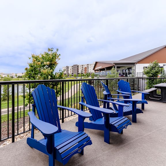 a set of blue chairs and a table are on a patio.