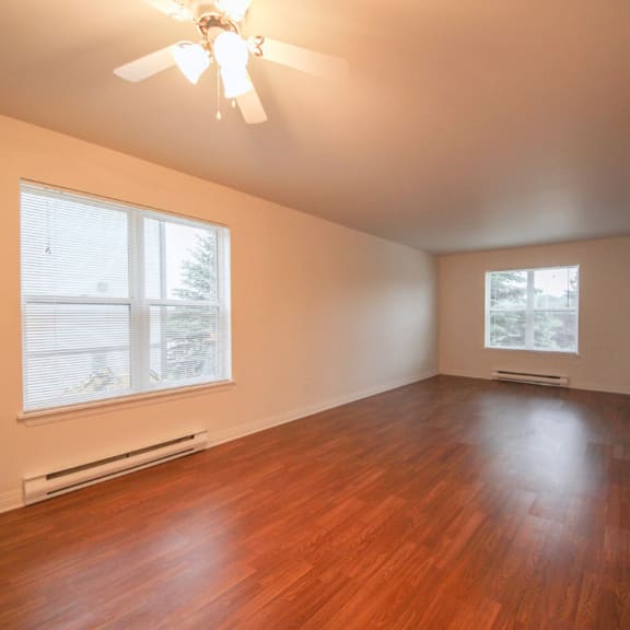a room with a ceiling fan and wooden flooring.
