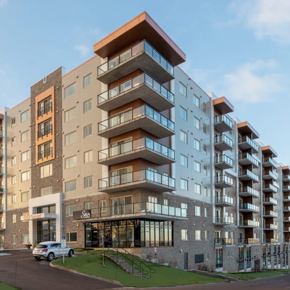a modern apartment building with cars parked in front.