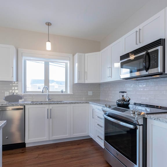 a kitchen with white cabinets and a stainless steel dishwasher.