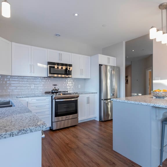 a modern kitchen with white cabinets and a marble countertop.