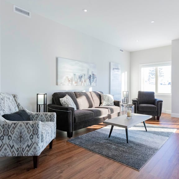 a living room with a grey patterned armchair, a black couch, and a coffee table.