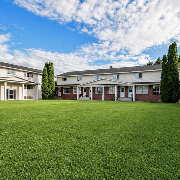 a row of houses with a green lawn in front.