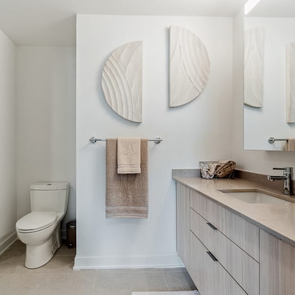 a bathroom with a toilet, a towel rack with a towel, and a mirror above a sink.