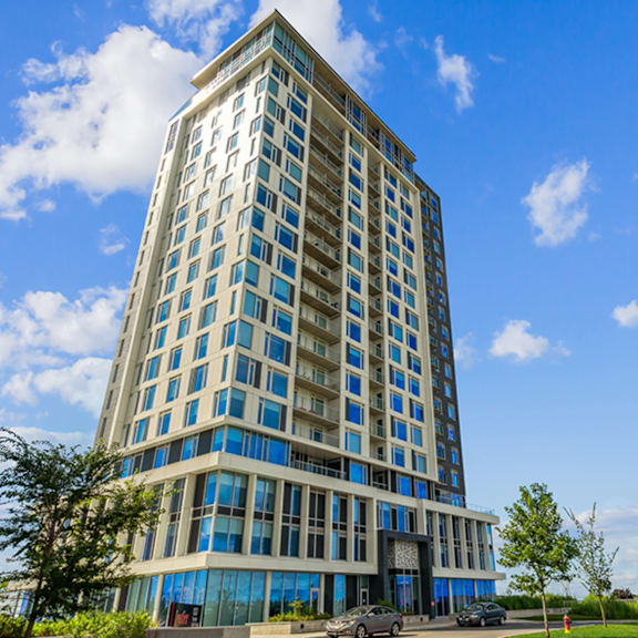 a tall building with many windows and cars parked in front.