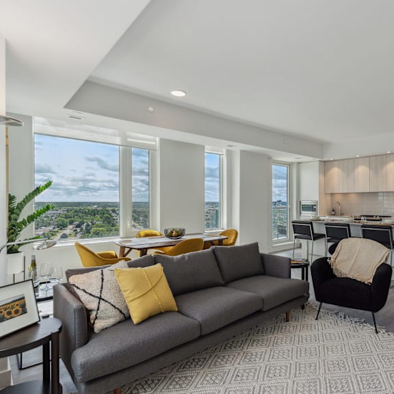 a grey couch with yellow pillows sits in a living room with a view of the city.