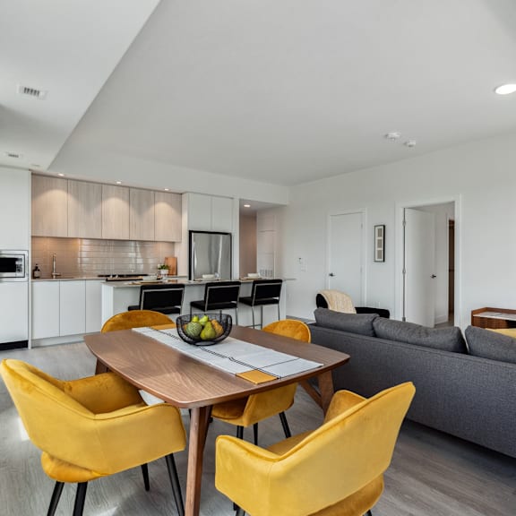 a modern kitchen with a dining table and yellow chairs.