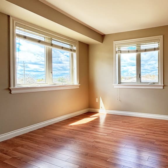 a room with wooden floors and two windows.