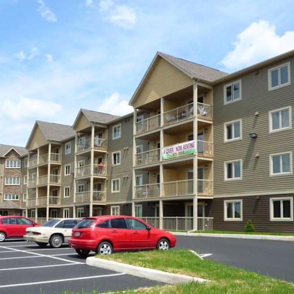 a row of apartment buildings with a red car parked in front.