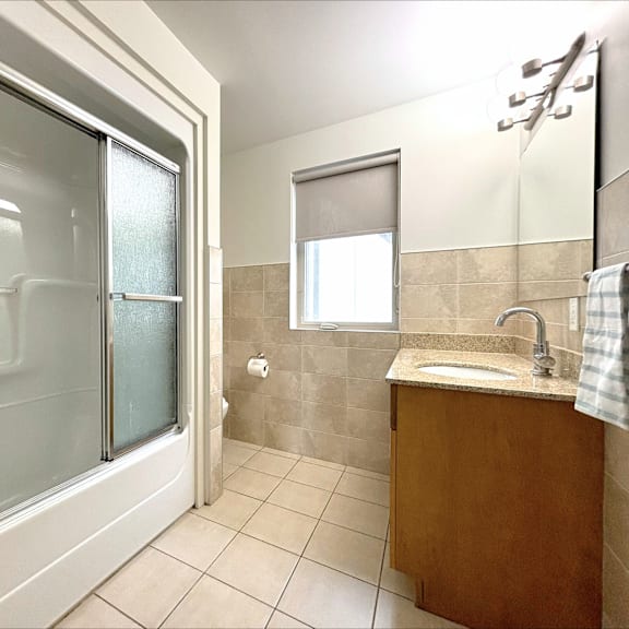 a bathroom with a sink, mirror, and shower.