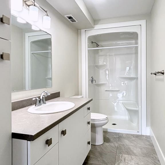 a white bathroom with a sink, toilet, and shower.