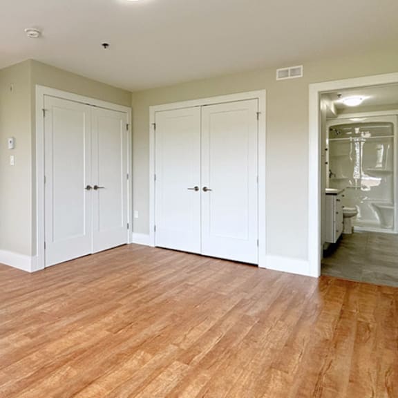 a room with white doors and wooden floors.