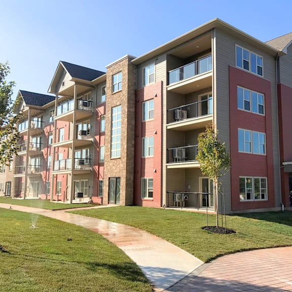 a multi-story apartment building with a walkway in front.
