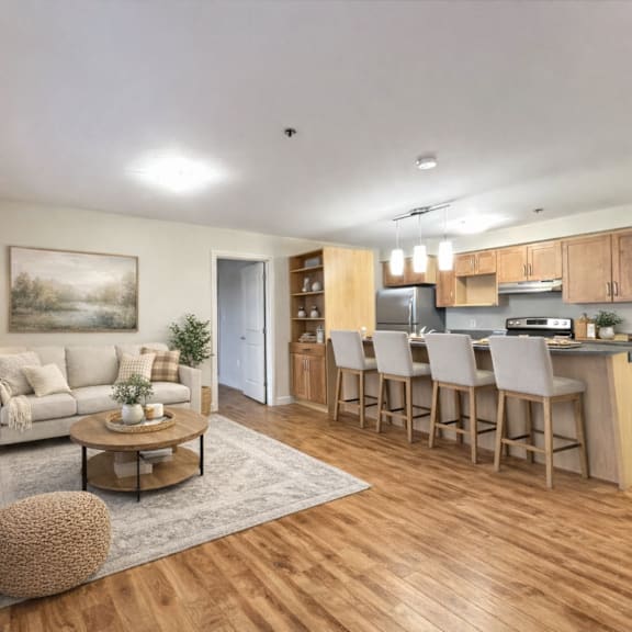 a well-lit, spacious kitchen and living room with wooden floors and furniture.