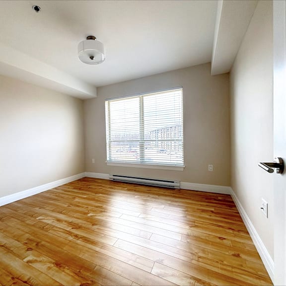 a room with wooden flooring and a window with blinds.