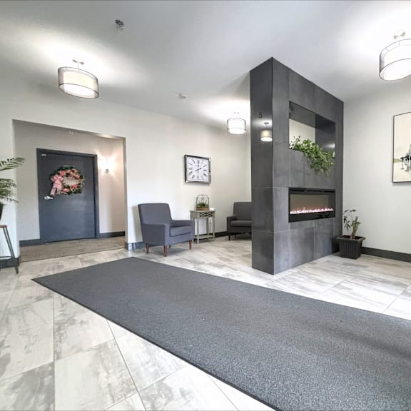 a modern living room with a grey rug and a fireplace.