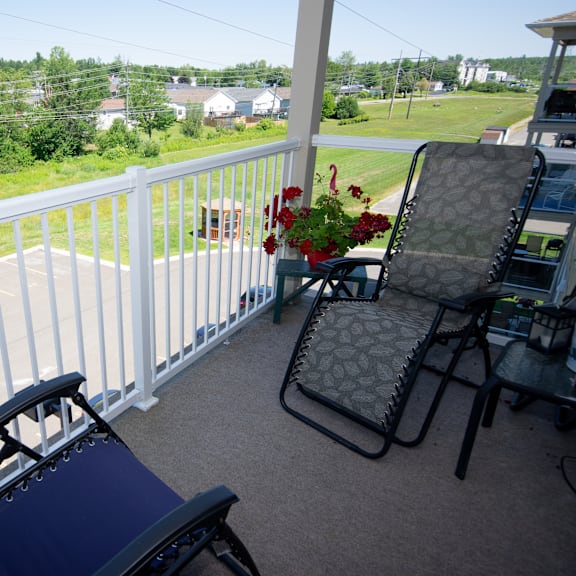 a chair and a table with a flower pot on a balcony.