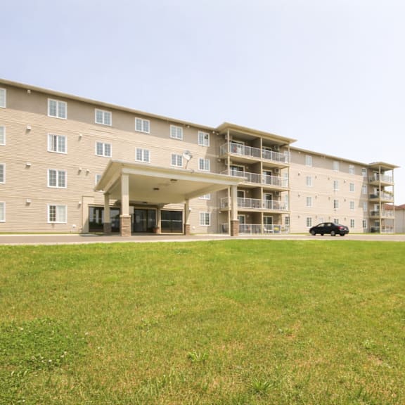 a large apartment complex with a car parked in the driveway.