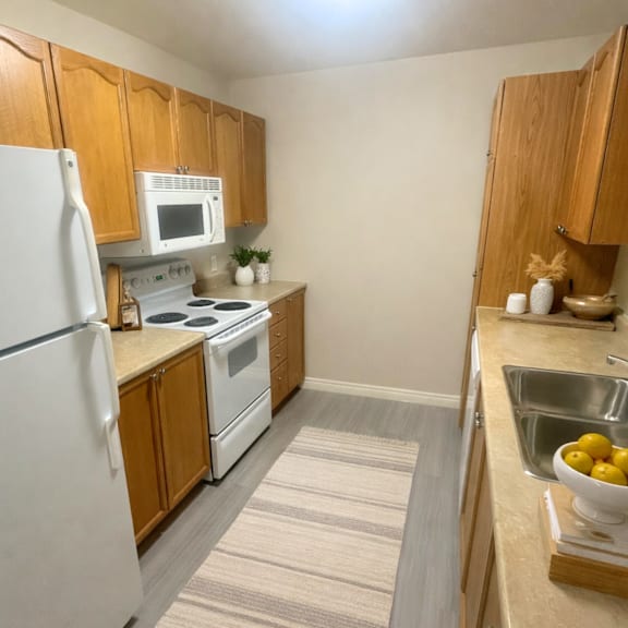 a kitchen with a white refrigerator, white stove, and wooden cabinets.