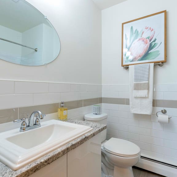 a bathroom with a sink, toilet, and a painting of a flower.