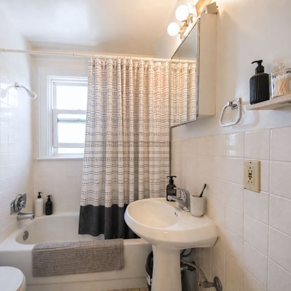 a white sink is on a white pedestal in a white tiled bathroom.