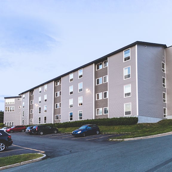 a large apartment building with a parking lot in front.