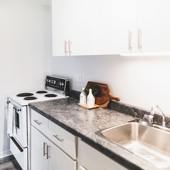 a kitchen with a stove, sink, and cabinets.