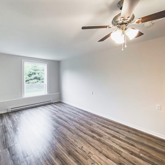 a room with a ceiling fan and wooden flooring.