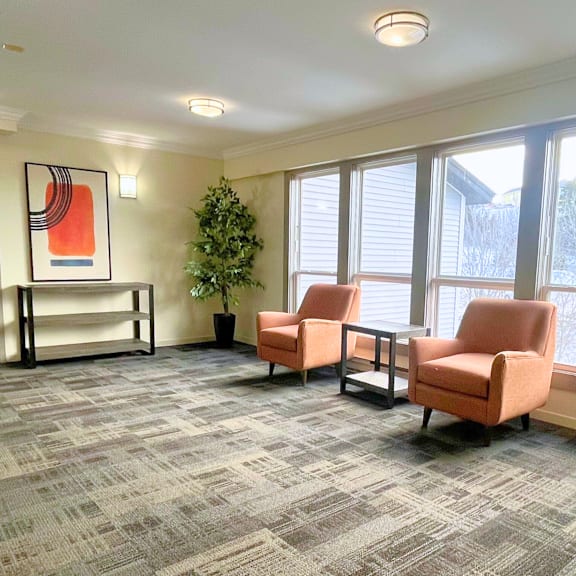 a room with two chairs and a table with a potted plant.