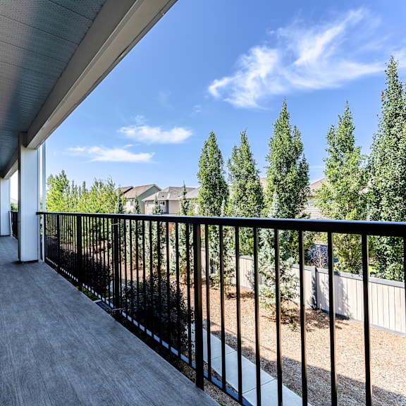 a balcony with a black railing and a view of trees and houses.