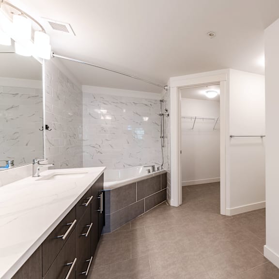 a bathroom with a marble tile wall and a white sink.