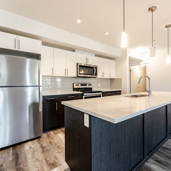a modern kitchen with a large island and stainless steel appliances.