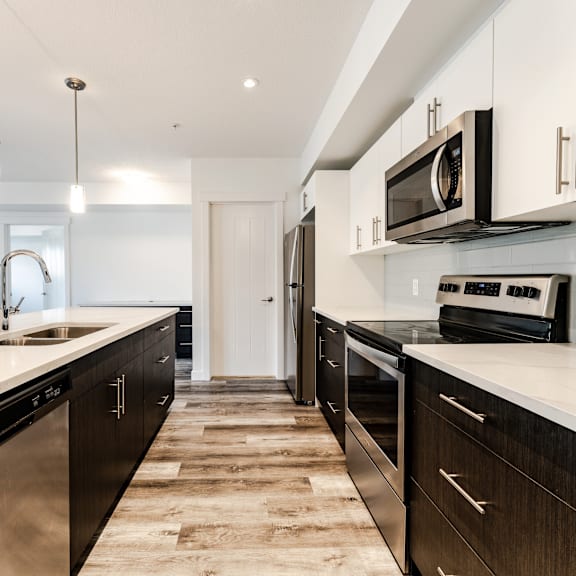 a modern kitchen with dark wood cabinets and stainless steel appliances.