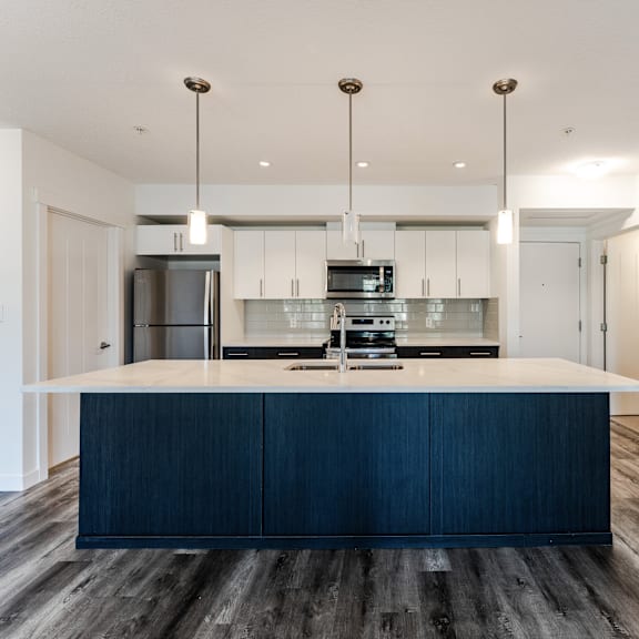 a modern kitchen with dark wood floors and white walls.