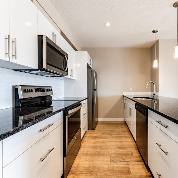a kitchen with black countertops and white cabinets.