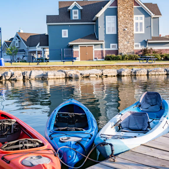 two kayaks, one red and one blue, are docked at a wooden pier.