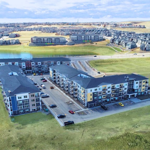 a large apartment complex with a parking lot in front.