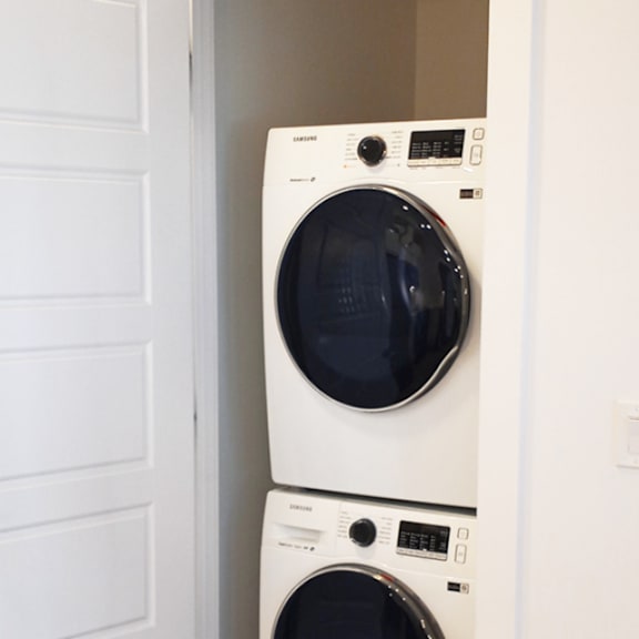 two white washing machines stacked in a doorway.