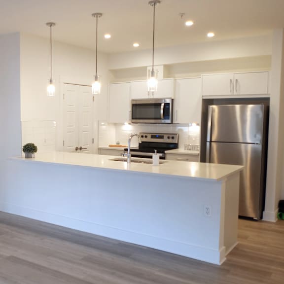 a modern kitchen with a white countertop and stainless steel appliances.