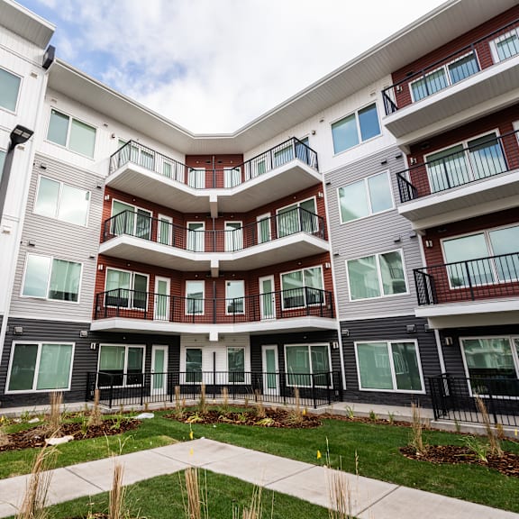 a modern apartment complex with balconies and a well-maintained lawn.