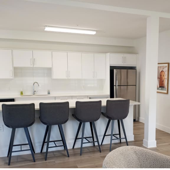four black barstools are placed in front of a white counter.
