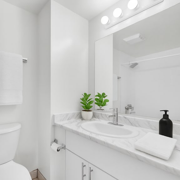 a white bathroom with a toilet, sink, and mirror.