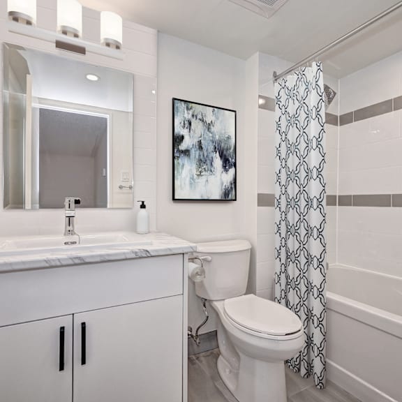 a white bathroom with a toilet, sink, and shower.