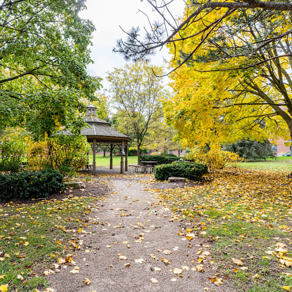 a gazebo sits in the middle of a park with a path leading to it.
