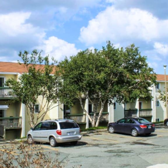 a silver minivan is parked in a parking lot in front of a white apartment building.