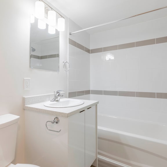 a white bathroom with a sink, toilet, and bathtub.
