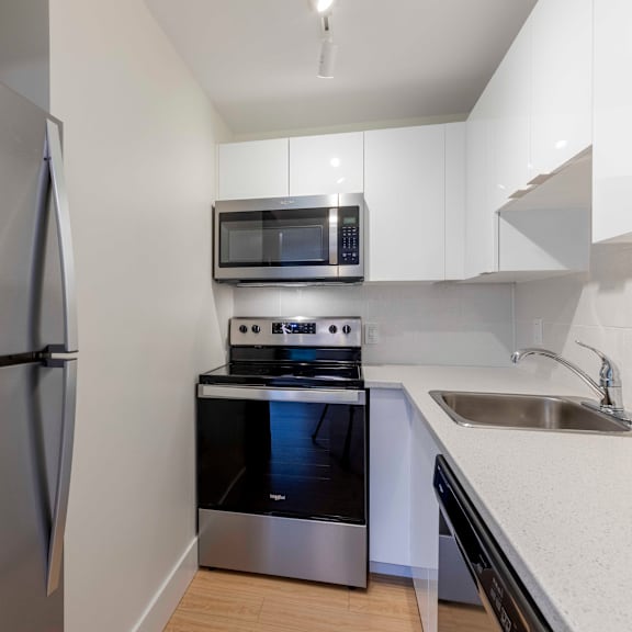 a kitchen with a stainless steel refrigerator, microwave, oven, and sink.