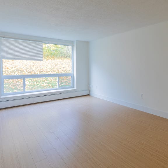 a room with a large window and wooden flooring.