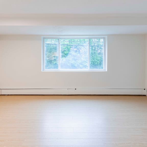 a room with a large window and wooden flooring.