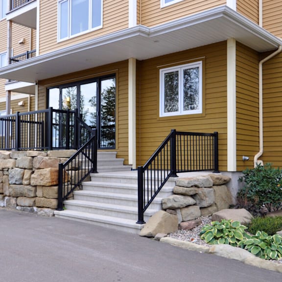 a brown house with a black railing on the stairs.